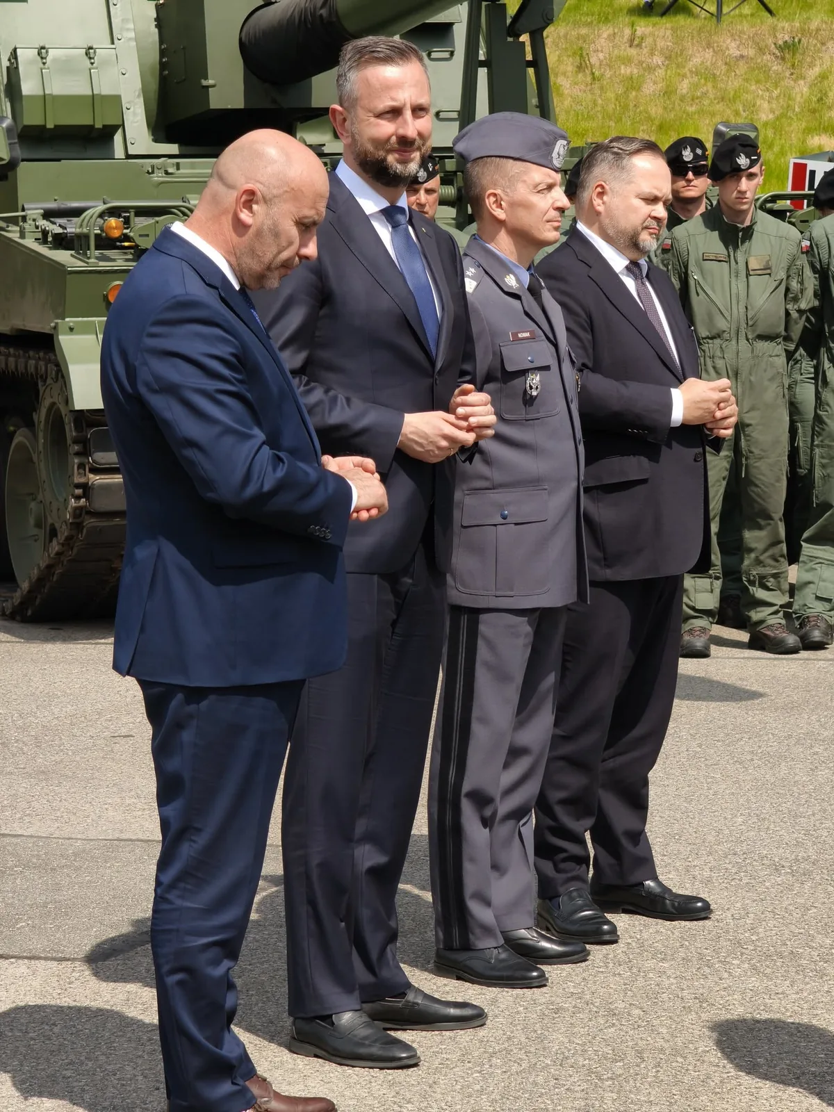 Uczestnicy wydarzenia i osoby w mundurach przy ekspozycji sprzętu wojskowego.